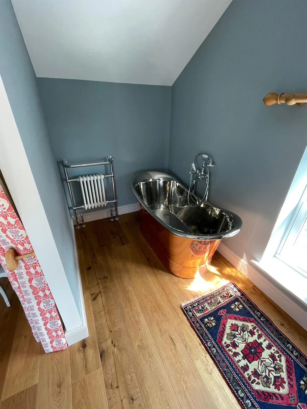 Luxury bathroom with copper bathtub and vintage rug.