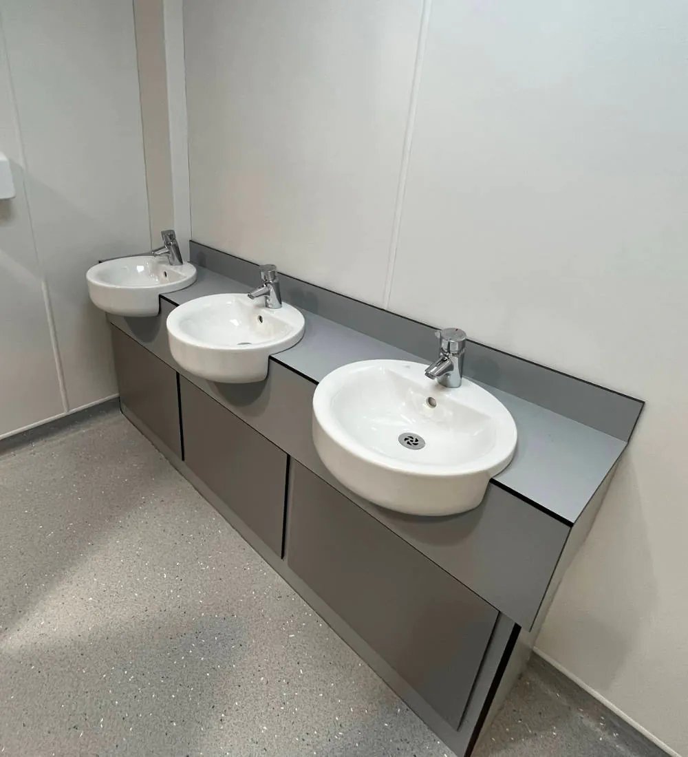 Three white sinks in public restroom.