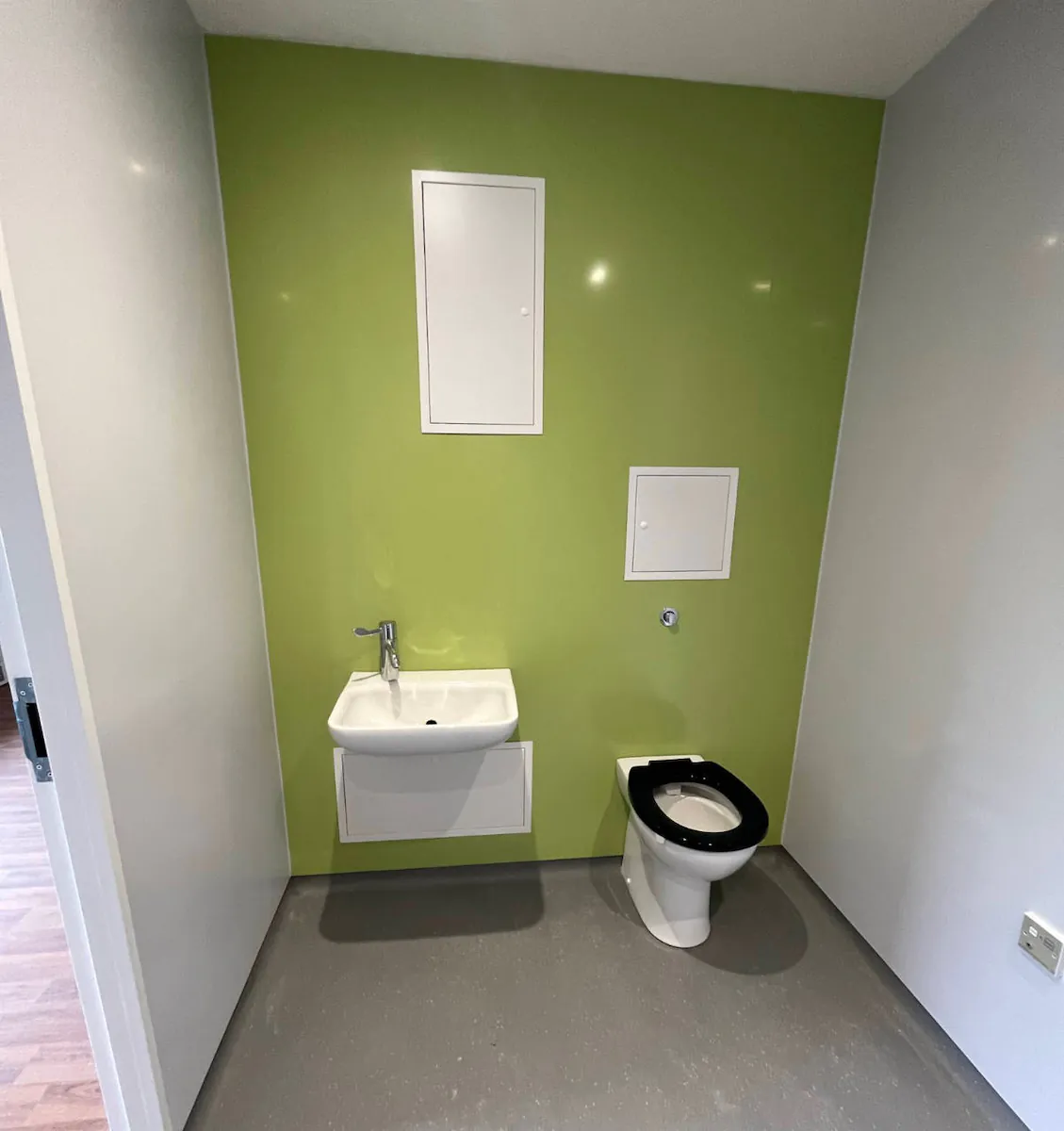 Minimalist bathroom with green wall and fixtures.