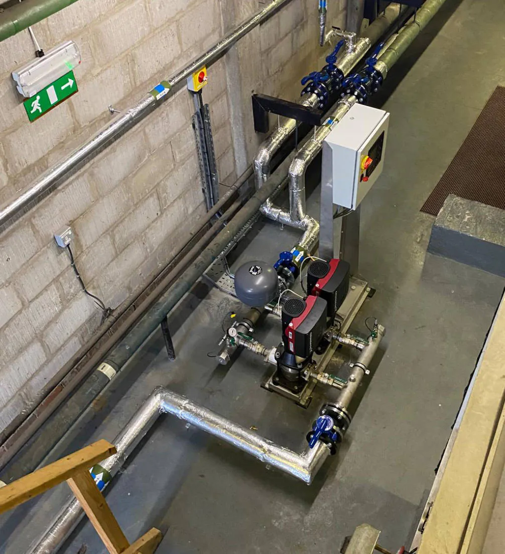 Industrial pipes and machinery in basement room.